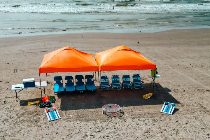 Orange tents with chairs on sandy beach near ocean.