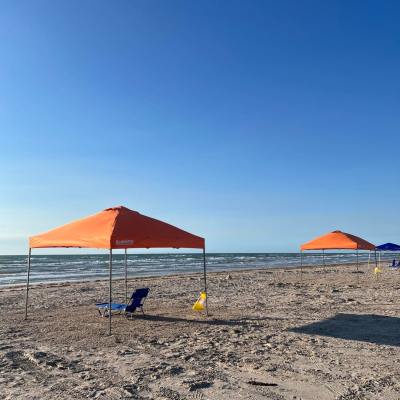 Two orange canopies on a sandy beach with blue sky and ocean.
