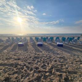 Rows of beach chairs facing the ocean at sunrise.
